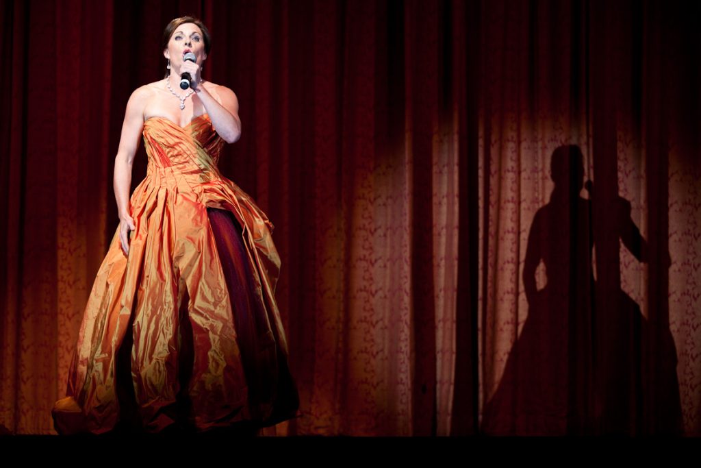 Singing Sommeliers vocalist performing on stage in an orange gown